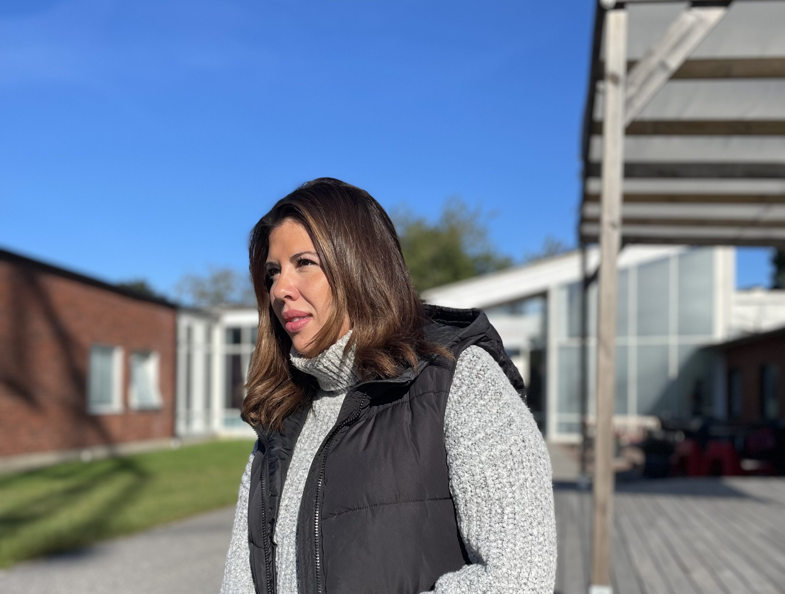Kvinna i väst med skola och himmel i bakgrunden