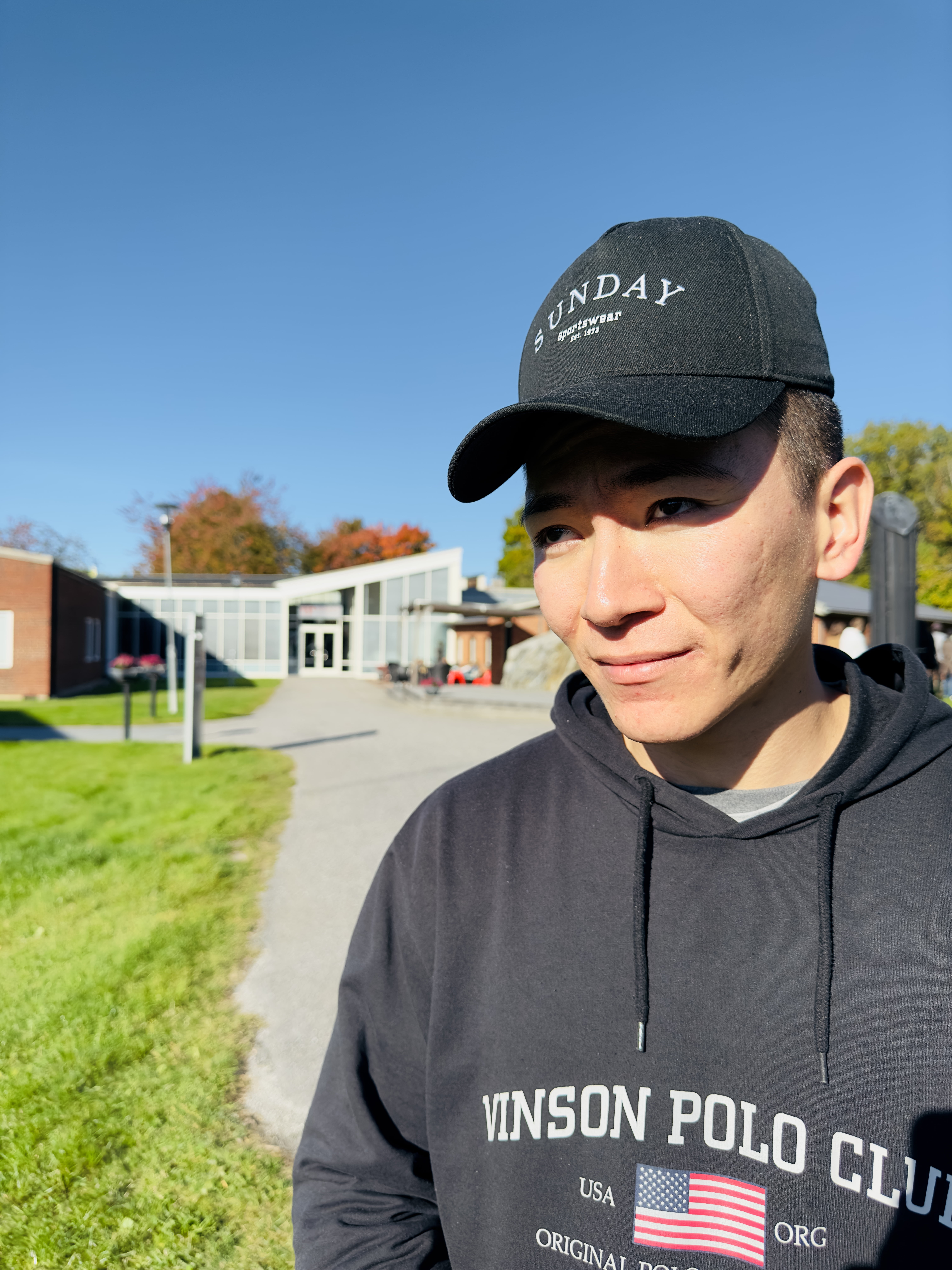 Kille med keps framför skolbyggnaden