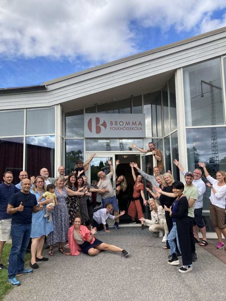 Skolans personal står uppställda framför huvudentrén.